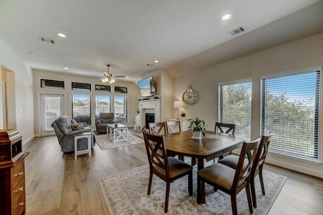 dining area featuring light wood-type flooring, visible vents, and a fireplace