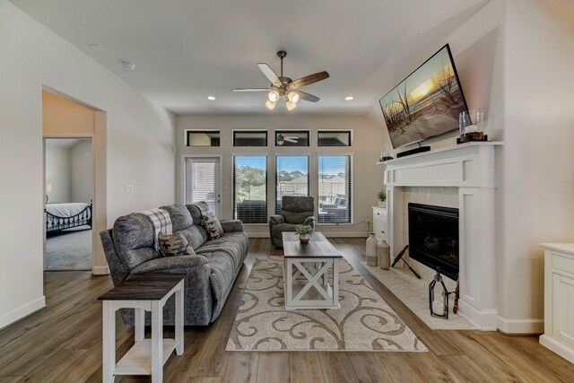 living room featuring recessed lighting, baseboards, light wood-type flooring, and a tile fireplace