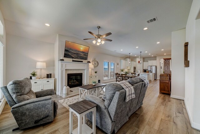 living area featuring light wood-type flooring, visible vents, recessed lighting, and a fireplace