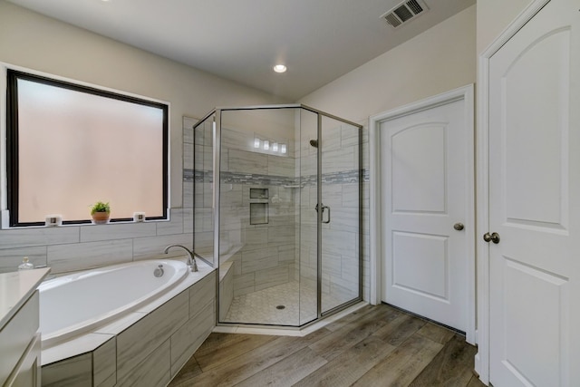 bathroom with a shower stall, a bath, wood finished floors, and visible vents