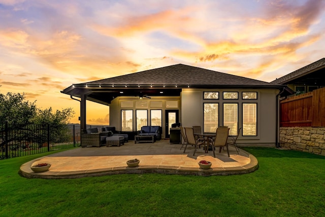 back of house at dusk with ceiling fan, fence, outdoor lounge area, a yard, and a patio area