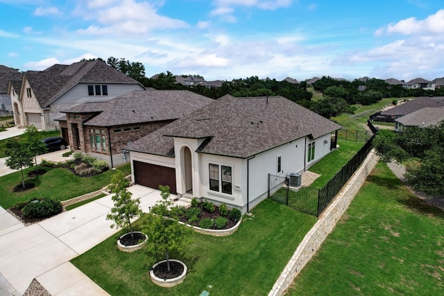 view of front of property featuring a front lawn, fence, roof with shingles, stucco siding, and driveway