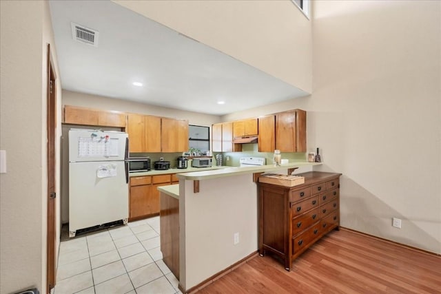 kitchen with kitchen peninsula, light hardwood / wood-style flooring, white fridge, and range