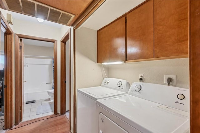 laundry area with cabinets, independent washer and dryer, and light hardwood / wood-style flooring