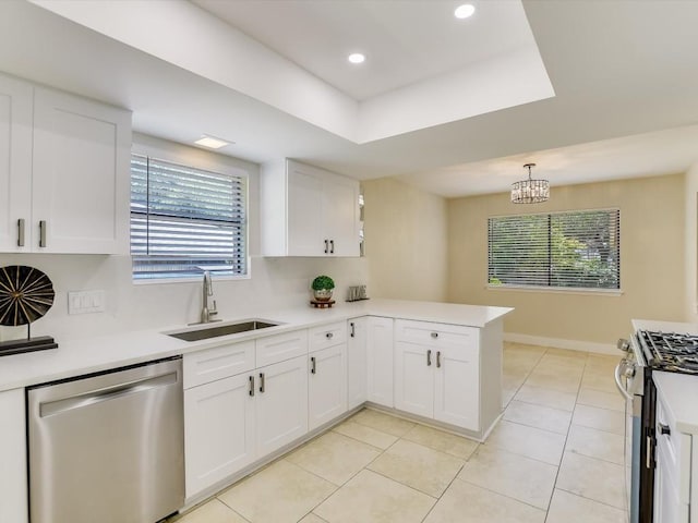 kitchen with appliances with stainless steel finishes, white cabinetry, sink, hanging light fixtures, and kitchen peninsula