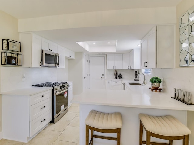 kitchen featuring white cabinetry, stainless steel appliances, sink, and a breakfast bar area