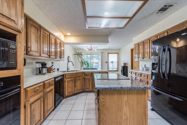 kitchen featuring black appliances, a center island, kitchen peninsula, and light tile patterned floors