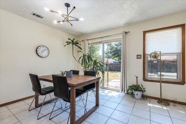 dining space featuring light tile patterned flooring, a textured ceiling, and a notable chandelier