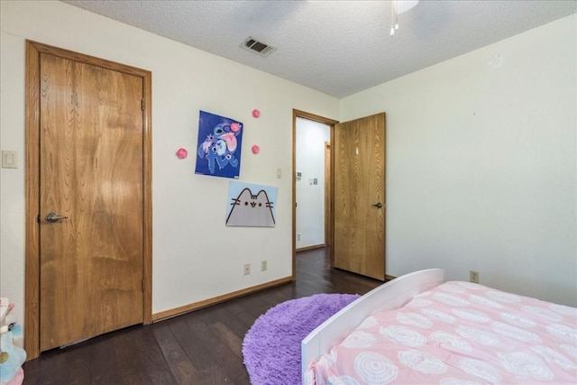 bedroom with a textured ceiling and dark wood-type flooring