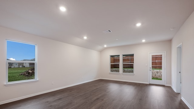 empty room with a healthy amount of sunlight, dark hardwood / wood-style floors, and lofted ceiling