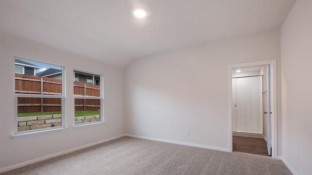 carpeted spare room featuring vaulted ceiling