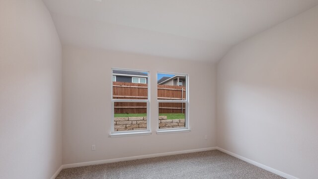 carpeted spare room featuring lofted ceiling