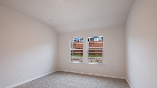 empty room with carpet flooring and vaulted ceiling