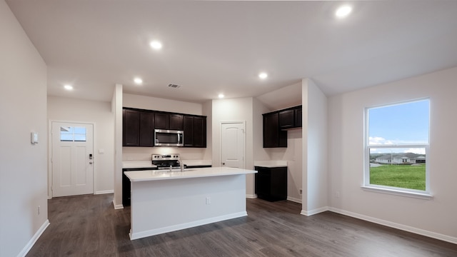 kitchen featuring stainless steel appliances, a kitchen island with sink, dark wood-type flooring, and sink