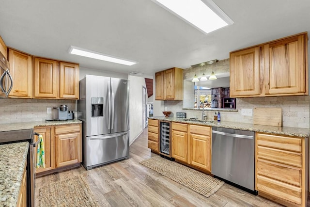 kitchen with light stone countertops, appliances with stainless steel finishes, light wood-type flooring, sink, and wine cooler