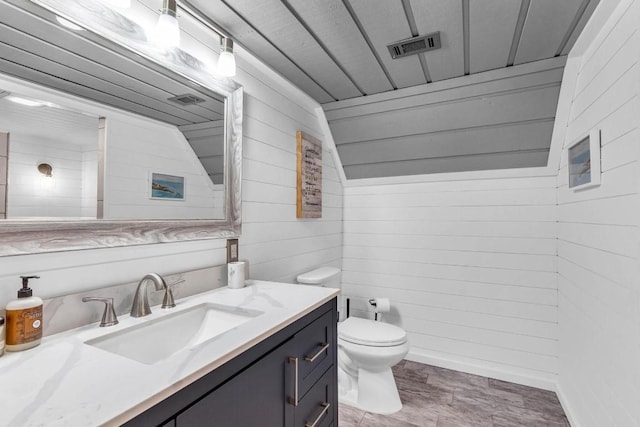 318 Coventry Rd, Spicewood, TX 78669 - bathroom featuring wooden walls, vanity, toilet, and wood finished floors