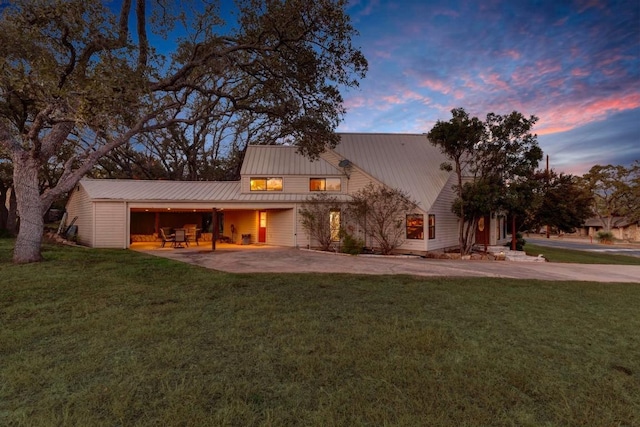 back house at dusk with a yard and a garage