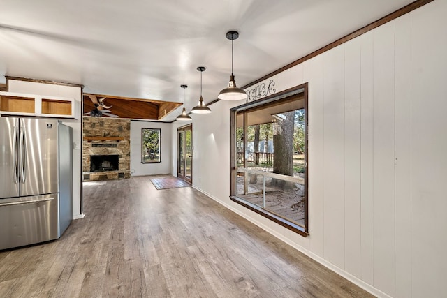 kitchen featuring ceiling fan, decorative light fixtures, a fireplace, hardwood / wood-style floors, and stainless steel refrigerator