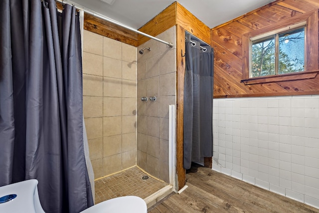 bathroom featuring curtained shower, wooden walls, toilet, and hardwood / wood-style flooring