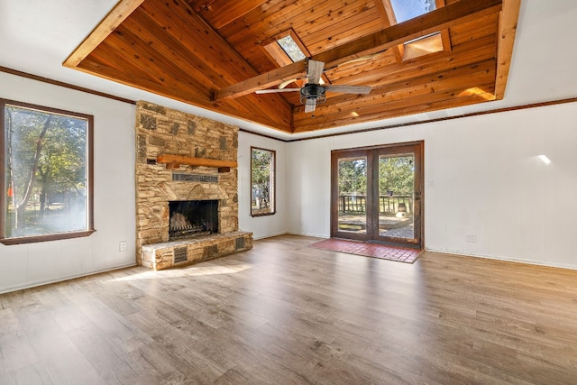 unfurnished living room featuring a skylight, ceiling fan, a fireplace, beam ceiling, and wood ceiling