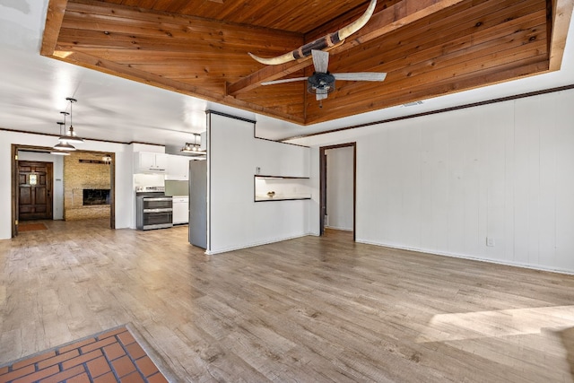 unfurnished living room featuring ceiling fan, a brick fireplace, light hardwood / wood-style floors, a tray ceiling, and wood ceiling