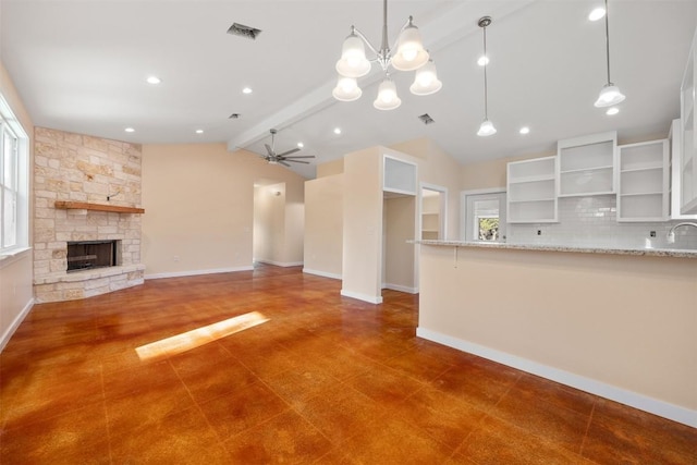 unfurnished living room featuring dark tile patterned flooring, ceiling fan with notable chandelier, sink, vaulted ceiling with beams, and a fireplace