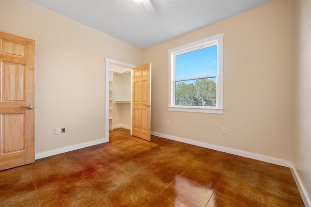 unfurnished bedroom with ceiling fan, a spacious closet, and a closet