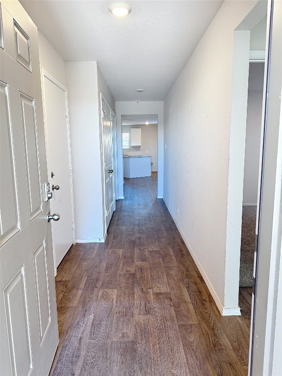 hallway featuring a textured ceiling and dark hardwood / wood-style flooring