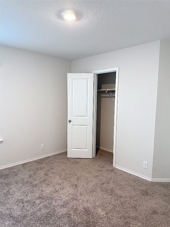 unfurnished bedroom with carpet flooring, a textured ceiling, and a closet