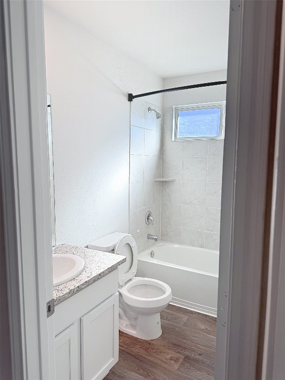 full bathroom with toilet, vanity, tiled shower / bath combo, and hardwood / wood-style flooring