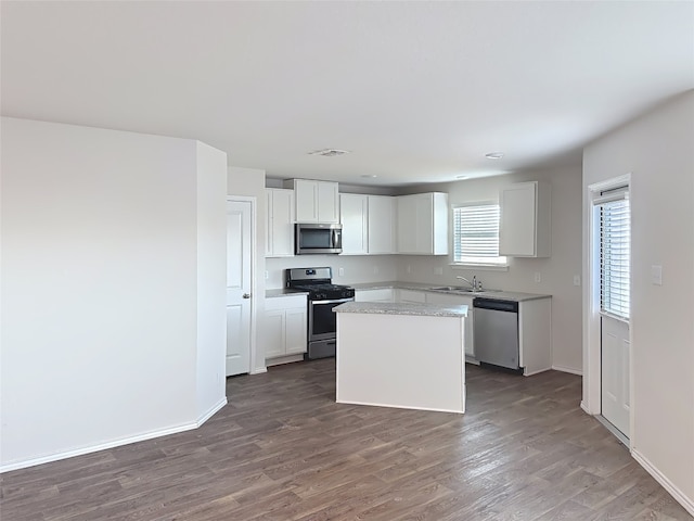 kitchen with sink, white cabinets, dark hardwood / wood-style floors, a kitchen island, and appliances with stainless steel finishes