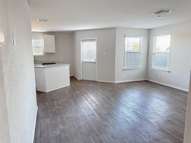 unfurnished living room with dark hardwood / wood-style flooring and a healthy amount of sunlight