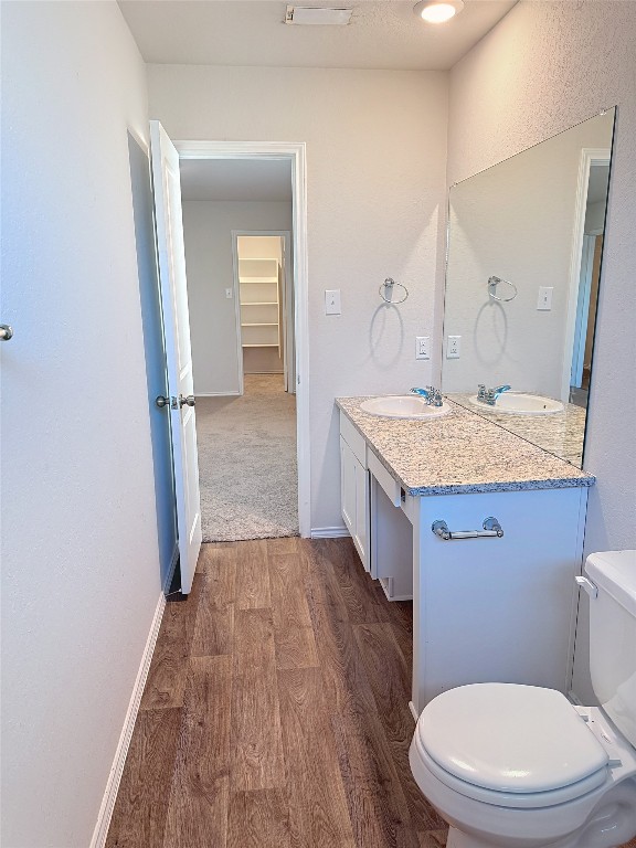 bathroom with hardwood / wood-style floors, vanity, and toilet