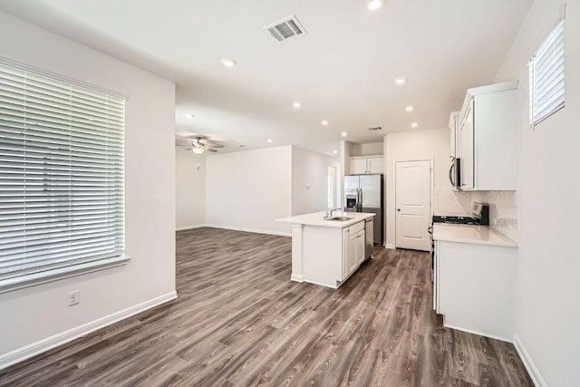188 Weaver Ln, Bastrop, TX 78602 - kitchen with stainless steel appliances, dark wood-type flooring, a ceiling fan, tasteful backsplash, and a center island with sink