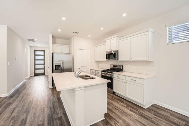 188 Weaver Ln, Bastrop, TX 78602 - kitchen featuring appliances with stainless steel finishes, a center island with sink, backsplash, dark wood-type flooring, and white cabinets