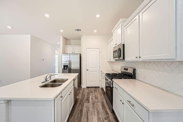 188 Weaver Ln, Bastrop, TX 78602 - kitchen featuring stainless steel appliances, dark wood-style floors, backsplash, white cabinetry, and an island with sink