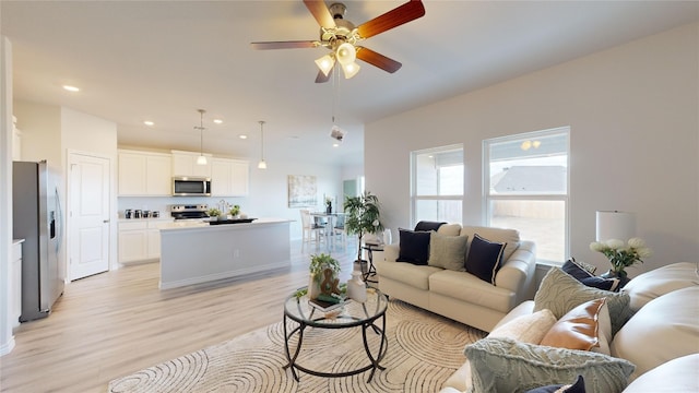 living room with light hardwood / wood-style flooring and ceiling fan