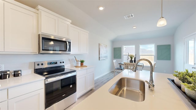 kitchen featuring stainless steel appliances, white cabinetry, hanging light fixtures, and sink