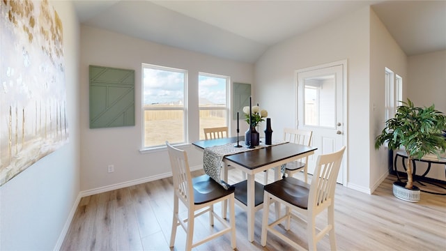 dining room with vaulted ceiling and light hardwood / wood-style flooring