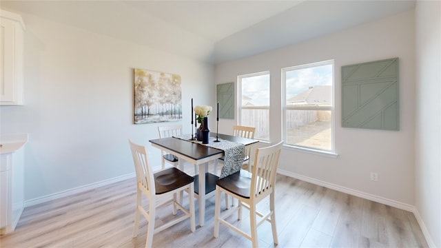 dining room with plenty of natural light, lofted ceiling, and light hardwood / wood-style flooring