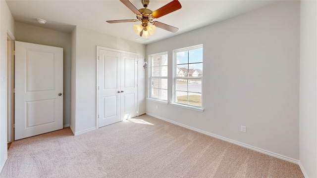 unfurnished bedroom featuring light colored carpet, a closet, and ceiling fan