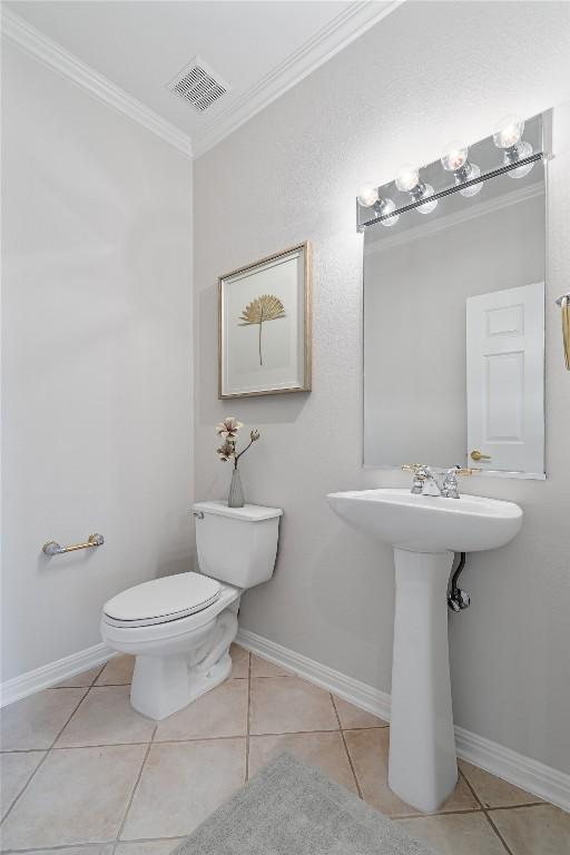 bathroom with tile patterned floors, crown molding, and toilet