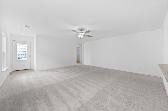 unfurnished living room featuring ceiling fan and light colored carpet