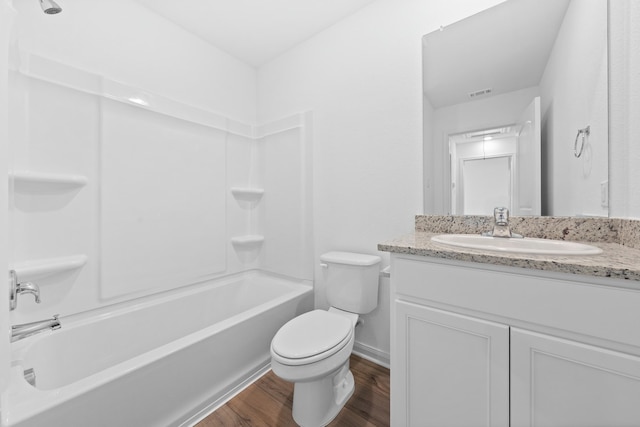 full bathroom with vanity, hardwood / wood-style flooring, washtub / shower combination, and toilet