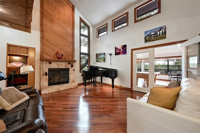 living room featuring a textured ceiling, a fireplace, high vaulted ceiling, and dark wood-type flooring