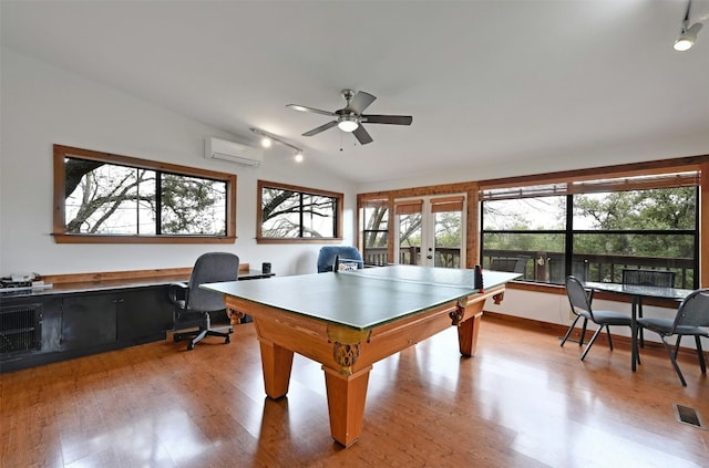 recreation room with french doors, a wall unit AC, ceiling fan, light hardwood / wood-style flooring, and lofted ceiling