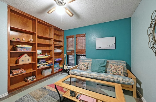 living area with ceiling fan, built in features, and a textured ceiling