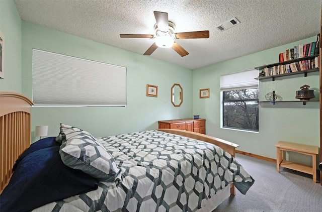 carpeted bedroom with ceiling fan and a textured ceiling