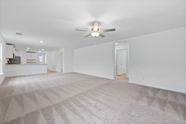 unfurnished living room featuring ceiling fan and light colored carpet