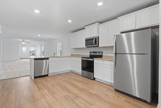 kitchen featuring kitchen peninsula, appliances with stainless steel finishes, ceiling fan, light hardwood / wood-style flooring, and white cabinets